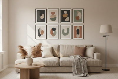 Gallery wall met kunstprints in zwarte lijsten symmetrisch opgehangen boven een beige bank, gelijke afstanden tussen de lijsten, minimalistisch Scandinavisch interieur