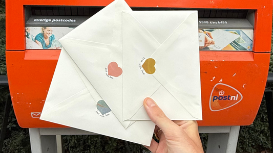 KOJO Art Print Club enveloppen met handgesigneerde limited edition prints, vintage postzegels en persoonlijke snailmail op een houten tafel met natuurlijk licht