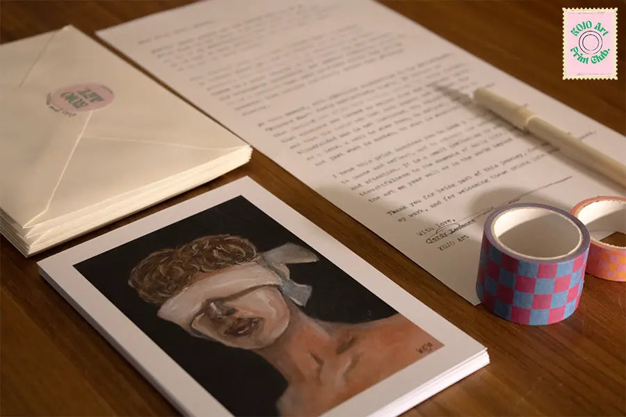 Close-up van de KOJO Art Print Club met daarop zichtbaar een kunstprint, enveloppen, de persoonlijke brief, pen en washitape.